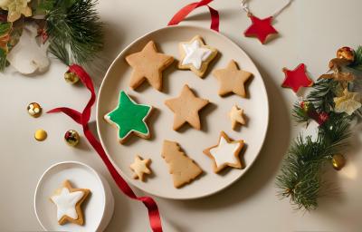 Fotografia em tons de vermelho e verde com um prato branco ao centro. Dentro do prato existe uma receita de biscoitos natalinos em formato de estrelinhas.