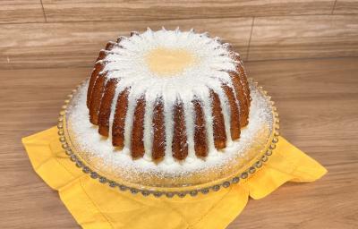 Fotografia em tons de amarelo com um prato de vidro ao centro. Em cima do prato existe um bolo em formato de estrela coberto com um brigadeiro de Leite NINHO e mais NINHO polvilhado