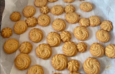 Foto em tons de bege da receita de petit four servida em diversas porções sobre uma forma circular forrada com papel manteigada