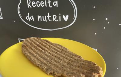 Imagem da receita de Pão de microondas sem glúten, em um prato amarelo e ao fundo uma lousa escrito em giz "Receita da nutri"