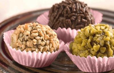 3 brigadeiros em forminhas lilás um com granulado por cima e os outros com castanhas picadas