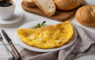 Fotografia mostra Omelete dourada servida dobrada no prato. Fotografia mostra Omelete dourada servida dobrada no prato.
