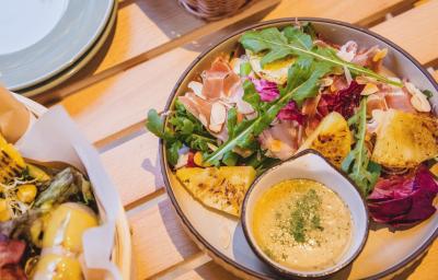 Fotografia de dois recipientes fundos de vidro com salada de abacaxi deliciosa feita com abacaxi, batata, presunto, uva-passa e um molho para acompanhar, no mesmo recipiente.