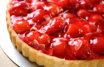 Fotografia de uma torta de morango com massa com Cereal NESTON e uma calda brilhosa por cima. A torta está sobre um fundo falso da forma.