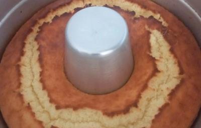 Foto da receita de Bolo de Arroz Cru. Observa-se um bolo assado ainda dentro de uma forma com furo no meio