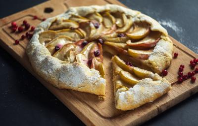 Fotografia em tons de marrom com uma tábua de madeira ao centro. Em cima da tábua existe uma torta rústica de maçã com a massa feita de NESTLÉ Farinha de aveia.