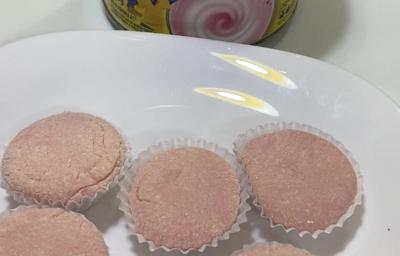 Fotografia de seis unidades de brigadeiro de nesquik em forminhas brancas, sobre um prato raso branco de vidro. Ao lado do prato tem uma embalagem de nesquik.