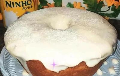 Foto da receita de Bolo de Ninho. Observa-se um bolo assado com furo no meio e bastante cobertura polvilhada de Leite Ninho