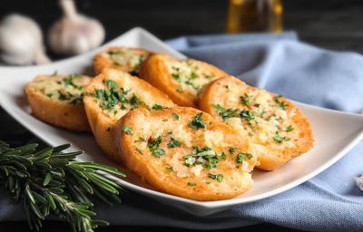 Fotografia em tons de branco com um prato branco ao centro. Em cima do prato existe uma receita de rabanada salgada com ervas e queijo parmesão