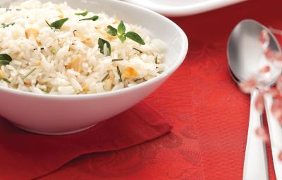 fotografia em tons de vermelho e branco, contém um pano vermelho e por cima um recipiente redondo branco com arroz e ao lado colheres para servir