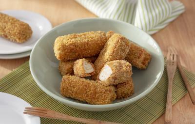 Foto da receita de Bolinho de Tofu. Observa-se uma tigela de porcelana verde clara com os bolinhos empanados dentro, sendo que um está cortado no meio. A tigela está sobre uma rede de sushi e uma superfície de madeira.