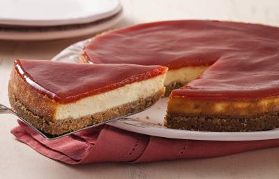 Fotografia em tons de branco e rosa de uma bancada branca com um paninho rosa, sobre ele um prato branco com torta de goiabada. Ao fundo dois pratos brancos.