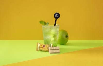 Foto da receita de Soda Italiana Apple Green. Observa-se um fundo amarelado e verde com um copo alto no centro, decorado com folha de hortelã. Uma maçã verde atrás do copo decora a foto.