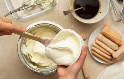 Foto da receita de Creme 4 Leites. Observa-se uma pessoa mexendo o creme dentro de uma vasilha branca.