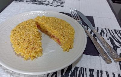 Imagem da receita de Cuscuz de frigideira recheado, sobre um prato branco e ao lado os talheres