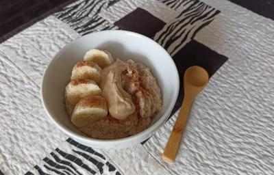 Imagem da receita de Mingau proteico pós treino, em um pote médio, sobre uma toalha e ao lado uma colher de madeira