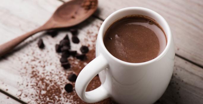 Foto da receita de Chocolate Quente. Observa-se uma xícara branca com a bebida cremosa dentro.