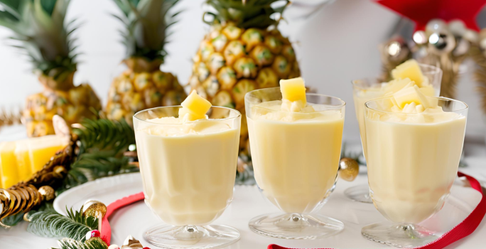 Receita de Delícia Gelada de Abacaxi, fácil e saborosa, feita com abacaxis em cubos, Leite MOÇA, NESTLÉ Creme de Leite e gelatina de abacaxi, servido em taças sobre uma mesa de natal