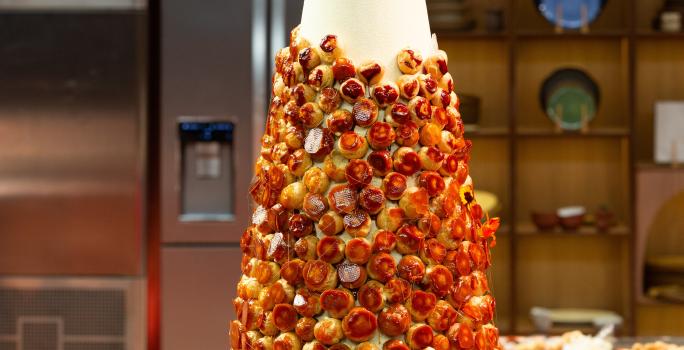 Fotografia em tons de caramelo com uma torre de choux com creme de confeiteiro com toque de laranja.