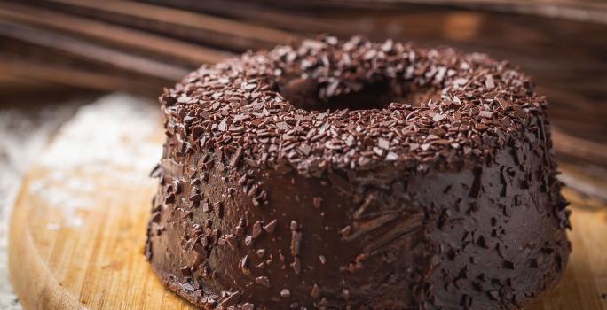 Foto da receita de Bolo de Chocolate. Observa-se um bolo com furo central e cobertura de brigadeiro.