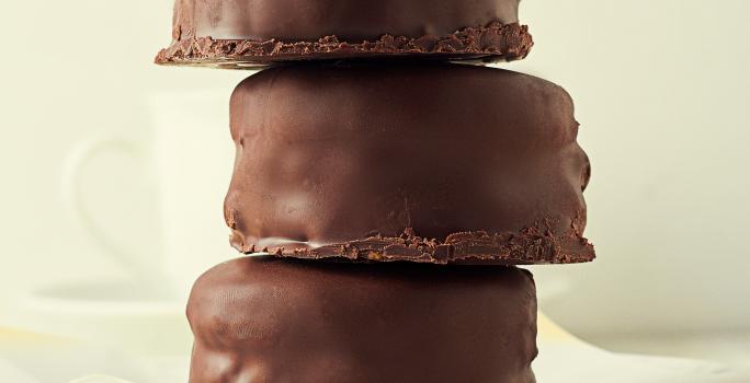 Fotografia de três pães de mel cobertos com chocolate, estão empilhados, um por cima do outro.arfo.