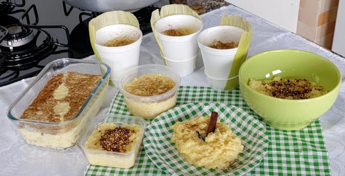 Fotografia de vários recipientes diferentes, sejam eles refratário de vidro, recipiente de vidro verde, prato colorido e copos grande de papel. Todos os recipientes têm dentro arros doce feito com milho verde e polvilhado com canela.