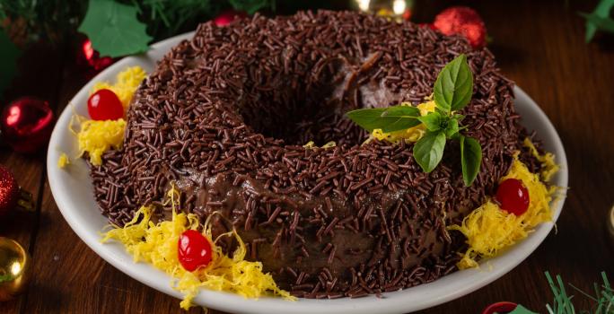 Receita de Brigadeirão de Natal, tradicional e delicioso, feito com Leite MOÇA, NESTLÉ Creme de Leite, Chocolate em Pó NESTLÉ CHOCOLATERIA, açúcar, ovos e margarina, decorado com fios de ovos, cerejas e sobre uma mesa de natal