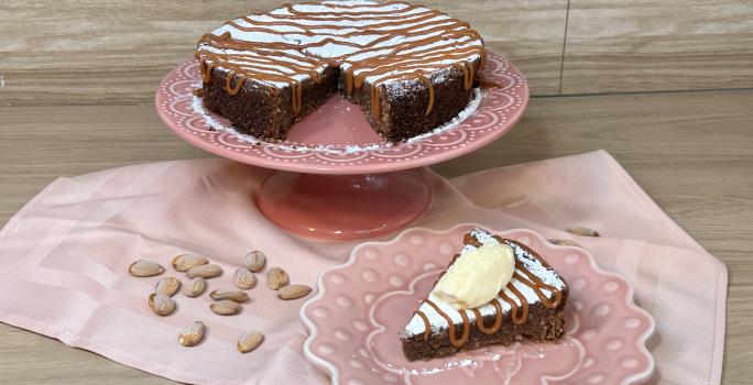 Fotografia em tons de rosa com uma toalha e um prato bailarina ao centro. Em cima do prato existe uma receita de torta italiana com recheio de chocolate e caramelo toffee