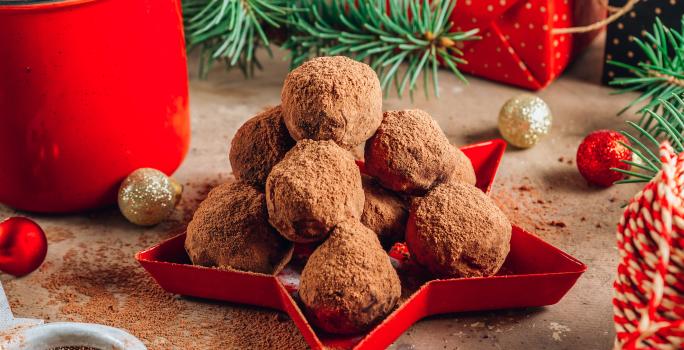 Fotografia mostra uma bandeja vermelha com trufas de chocolate perfeitas, cobertas com uma camada de chocolate em pó aveludado.