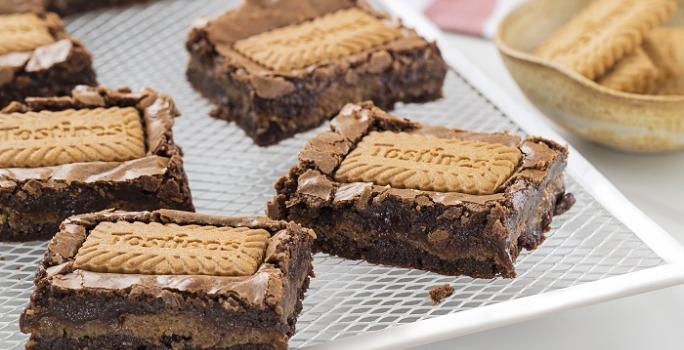 Foto da receita de Brownie de Tostines. Observa-se 5 fatias de brownie com o Biscoito TOSTINES Especiarias em cima e recheado de creme.