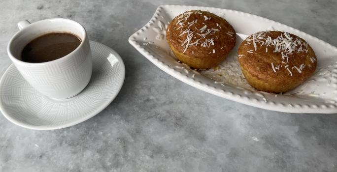 Imagem da receita de Muffin de Milho sem Glúten, em um recipiente branco e ao lado uma xícara de café