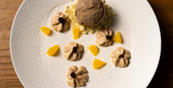 Receita de Café, Cardamomo e Laranja, delicioso e diferente, feito com Bolo de Amêndoa, Caramelo, Mousse de Laranja, Ganache Montada, Sorvete, Crumble Branco e decorado com Chocolate Branco