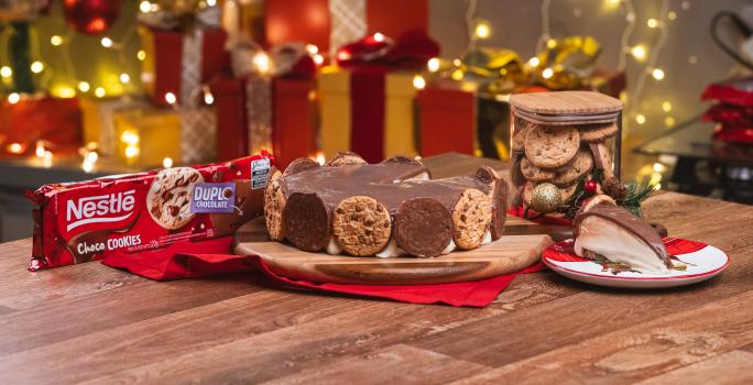 Foto da receita de Torta Holandesa de Chococookies. Observa-se uma torta holandesa com chococookies em volta e, ao lado direito, um pedaço da torta.