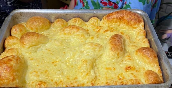 Fotografia de uma forma de alumínio retangular com o pão de queijo montanha russa preenchendo todo o recipiente.