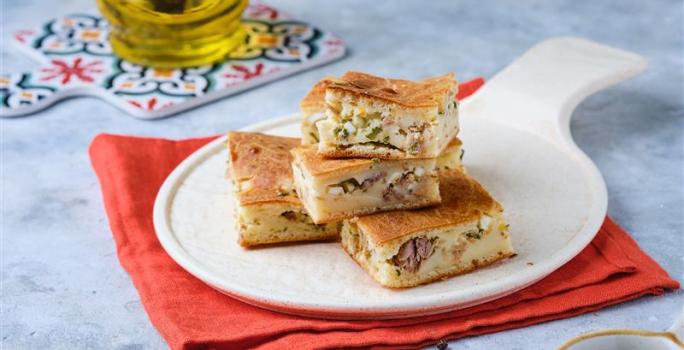 Fotografia mostra pedaços de torta de sardinha sobre um prato branco.