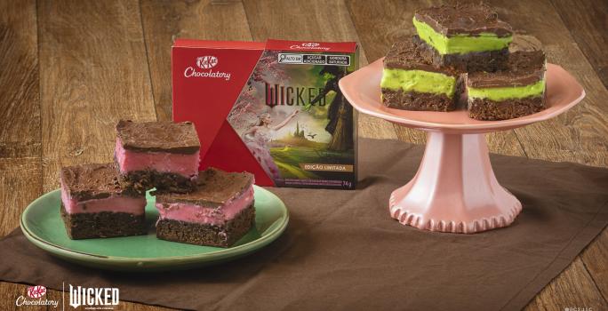 Receita de Brownie Wicked, servidos em pedaços de brownie de chocolate, metade com creme rosa e metade com creme verde, todos cobertos com Chocolate. Alguns em prato verde e outros em um prato rosa alto. No meio há uma caixa de KitKat Wicked.