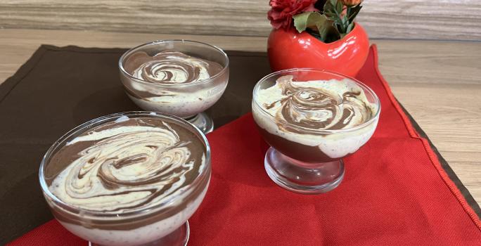 Fotografia de três recipientes com mousse de maracujá com creme de nescau mesclado. Os recipientes estão sobre um pano vermelho e um pano marrom de tom escuro.