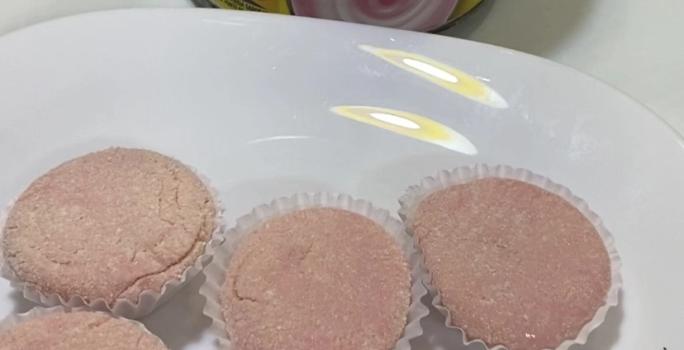 Fotografia de seis unidades de brigadeiro de nesquik em forminhas brancas, sobre um prato raso branco de vidro. Ao lado do prato tem uma embalagem de nesquik.