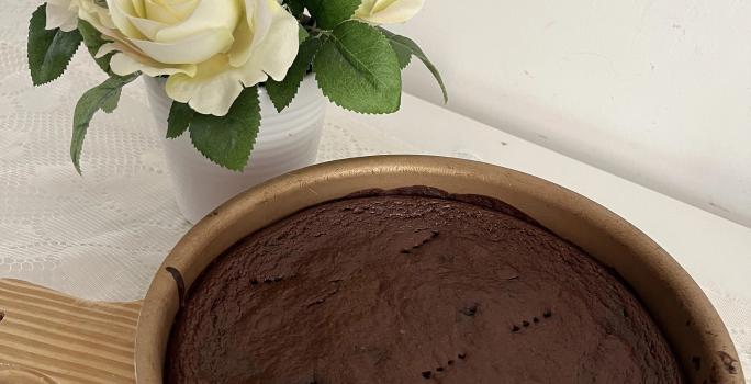 Fotografia de uma forma redonda antianderente com um brownie de chocolate e batata doce. A forma está sobre uma tábua de madeira.