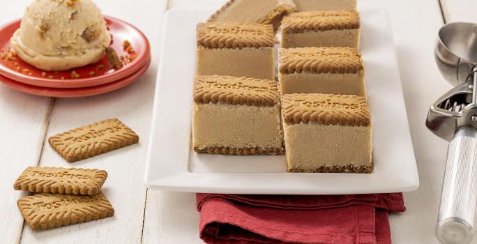 Fotografia de sete minisanduíches de sorvete de tostines sobre um prato retangular branco. Ao lado tem dois minis pratinhos vermelhos com uma bola de sorvete de tostines. Próximo ao prato tem três biscoitos tostines.